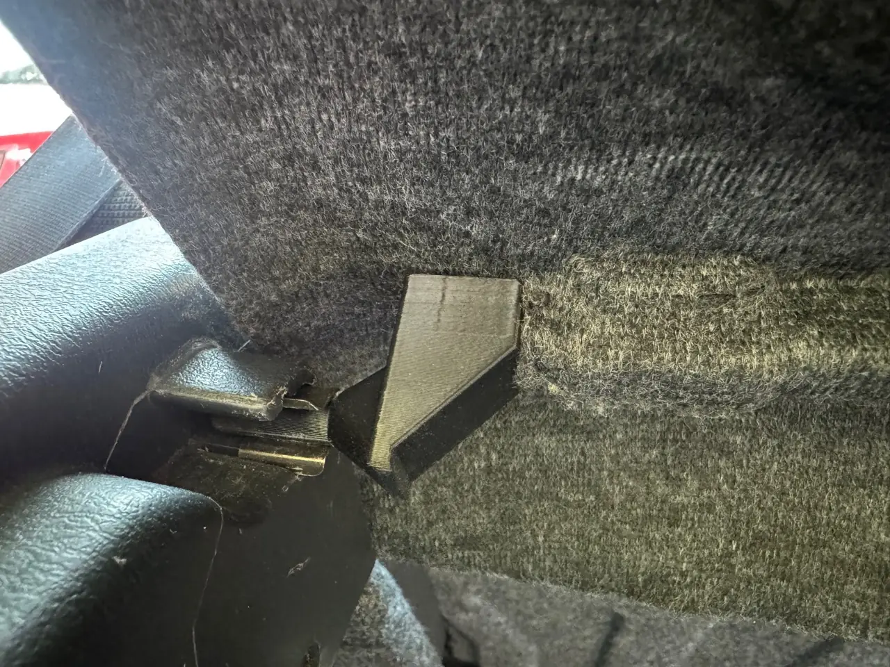 Replacement parcel shelf hinge fitted against the carpeted shelf at the original mounting point